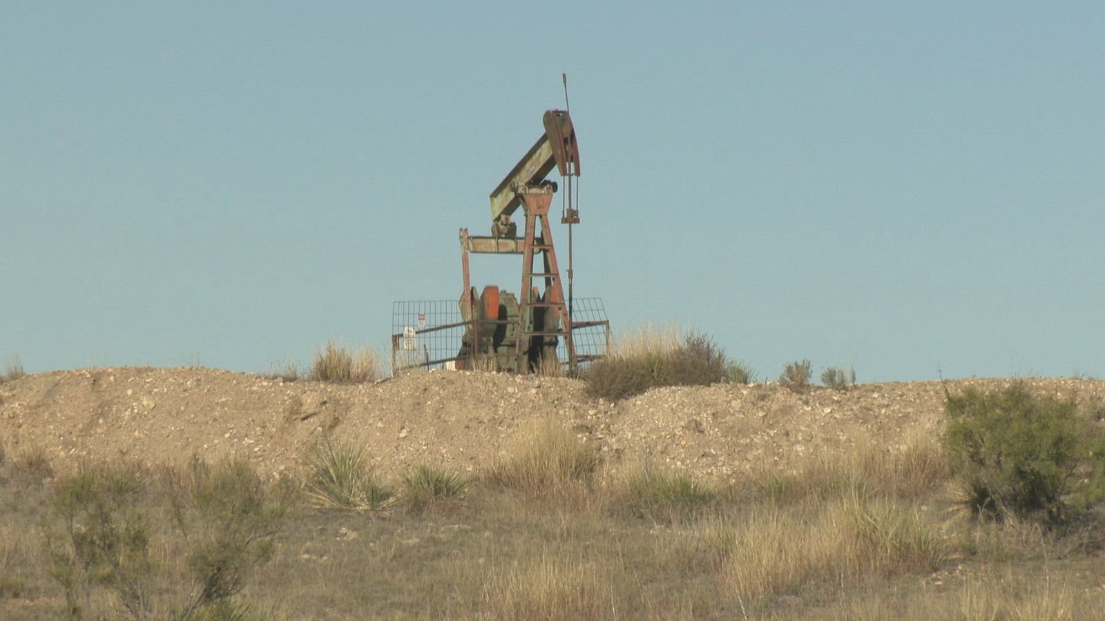 A small pumping unit on a raised pale pad among dry rangeland grass