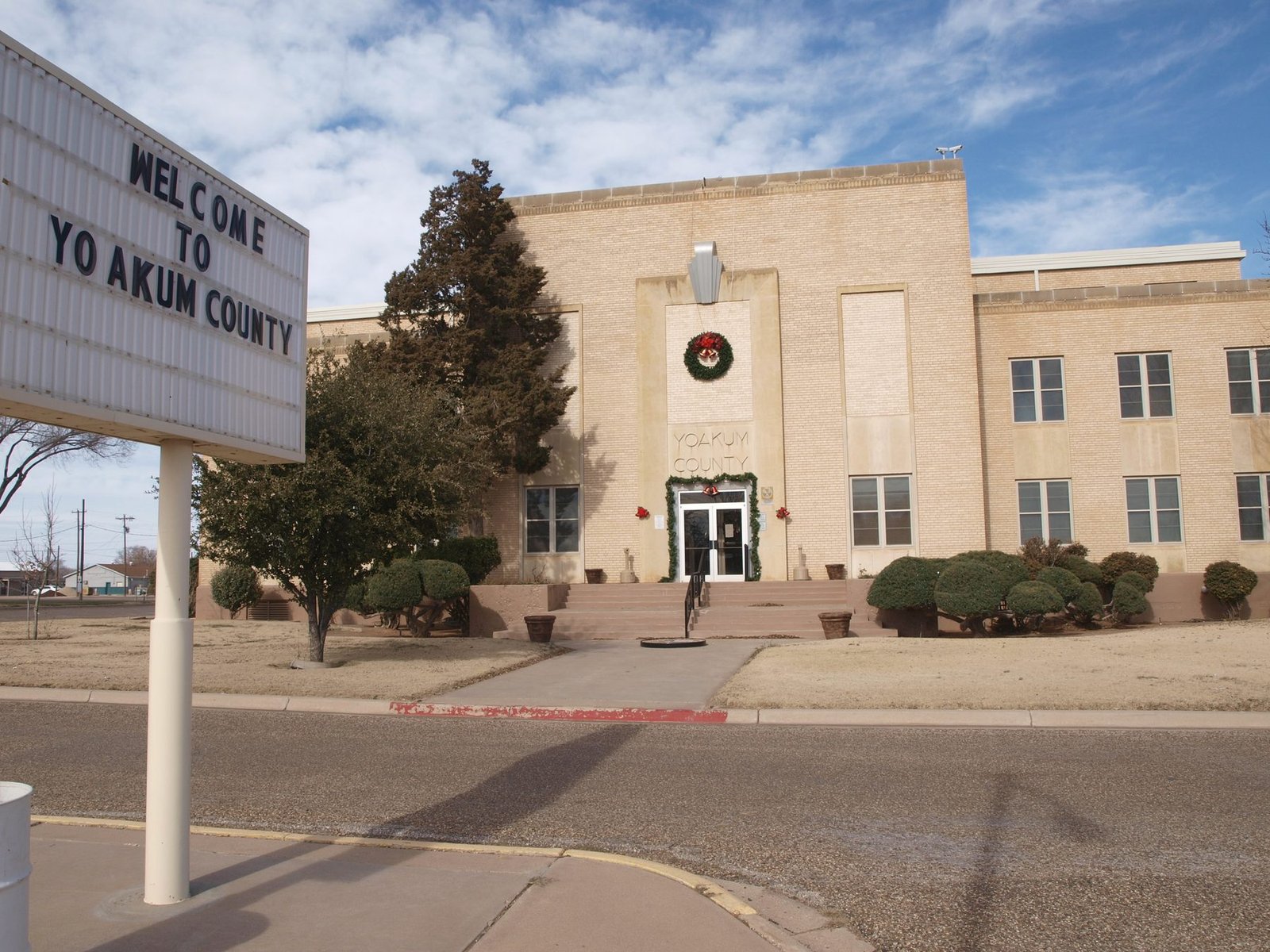 A Welcome to Yoakum County sign in front of the county courthouse